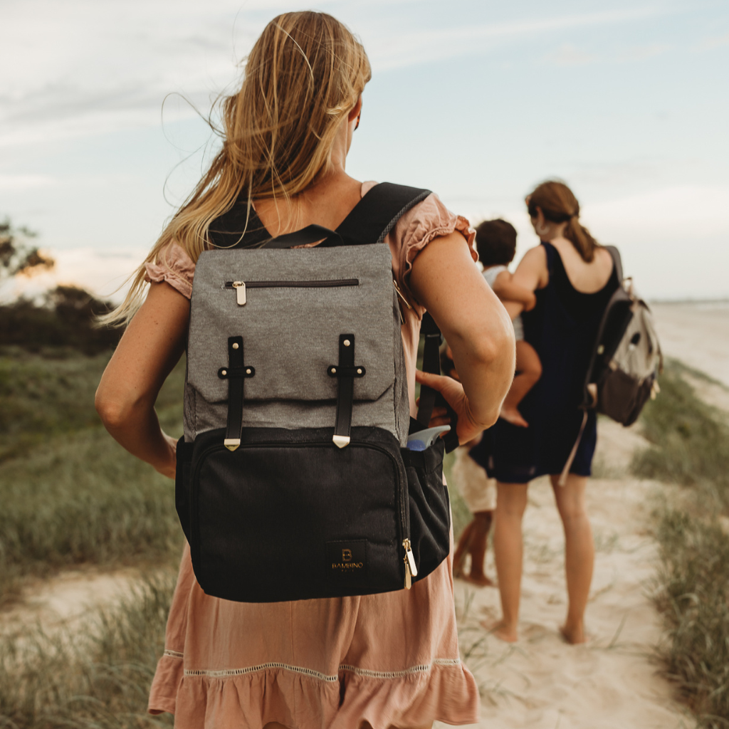 Sorrento nappy backpack - Best nappy bag.  Our Sorrento baby bag  in black and grey being worn by a Mum at the beach. The perfect unisex nappy bag