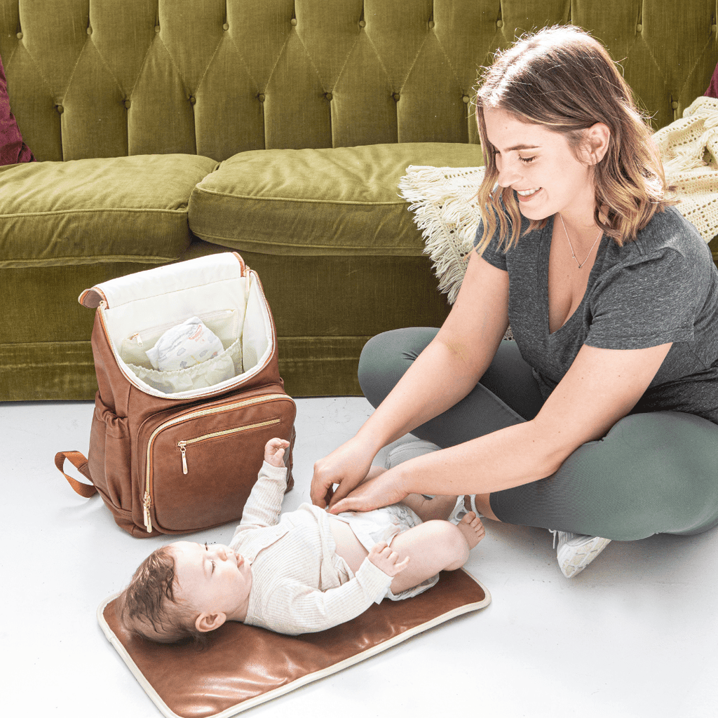 A new Mum changing her baby on the changing mat from the Florence baby bag backpack